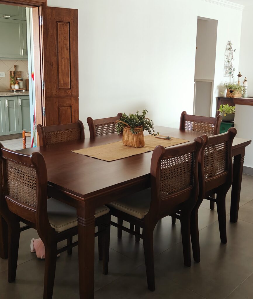 A six-seater teakwood dining table with chairs in cane | Girija home tour in Kochi