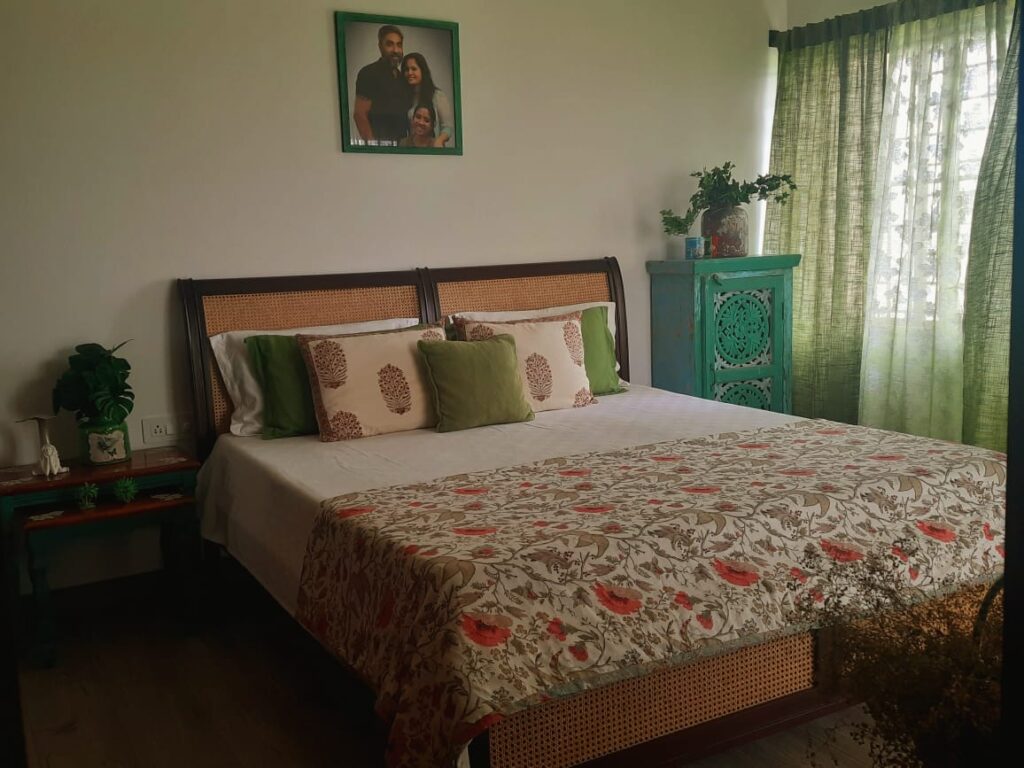 A beautiful teak bed with a cane headrest and interesting distressed furniture around the room | Girija home tour in Kochi