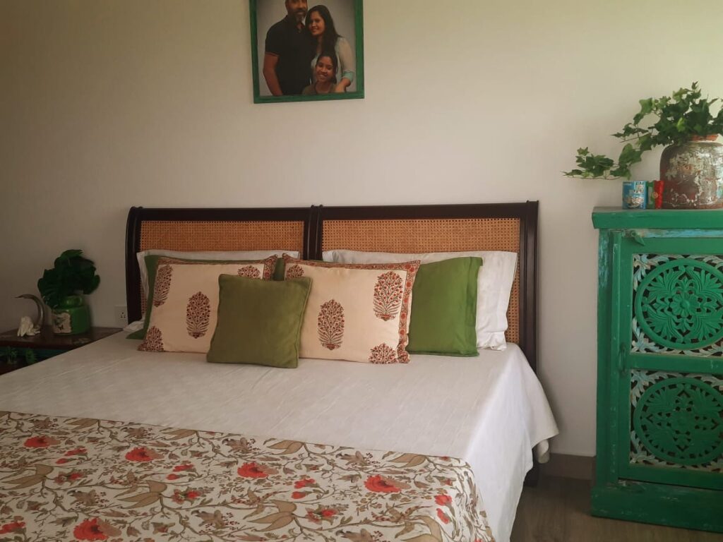 A beautiful teak bed with a cane headrest and interesting distressed furniture around the room | Girija home tour in Kochi