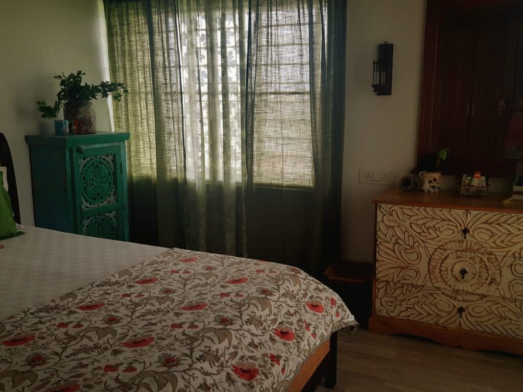 A beautiful teak bed with a cane headrest and interesting distressed furniture around the room | Girija home tour in Kochi